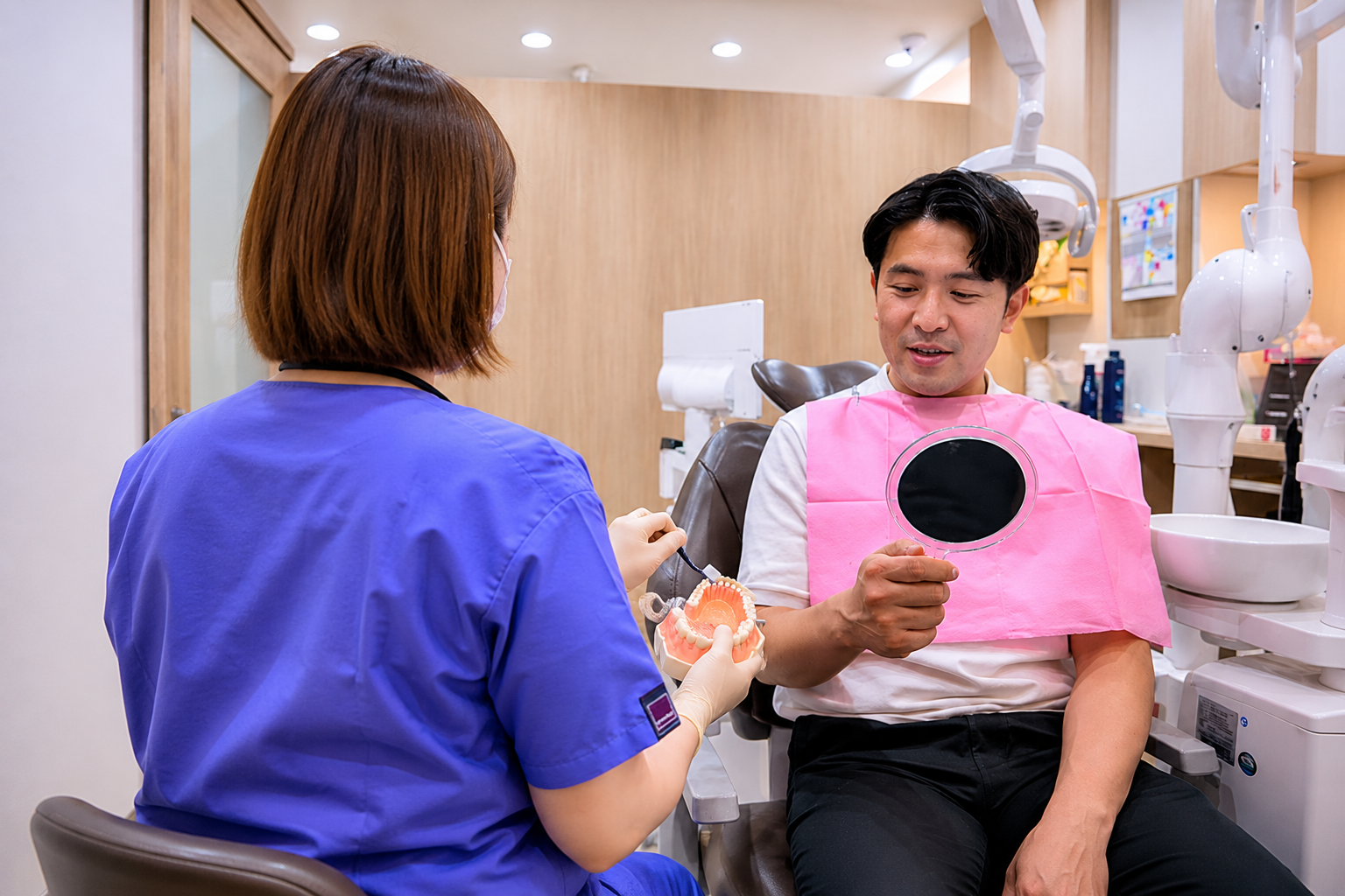 歯の模型を使って説明する歯科衛生士と患者さま