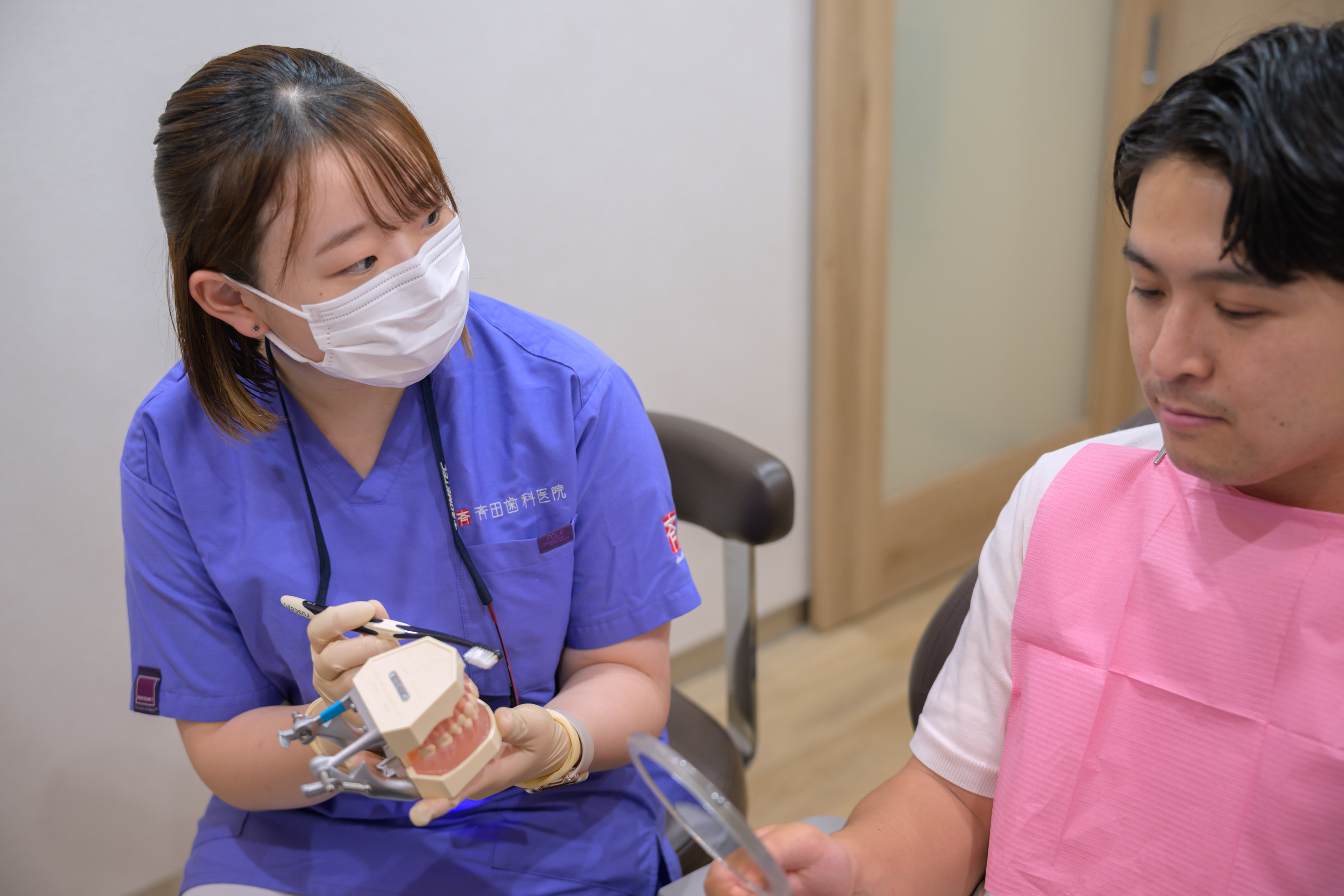 歯の模型を使って説明する歯科衛生士と患者さま