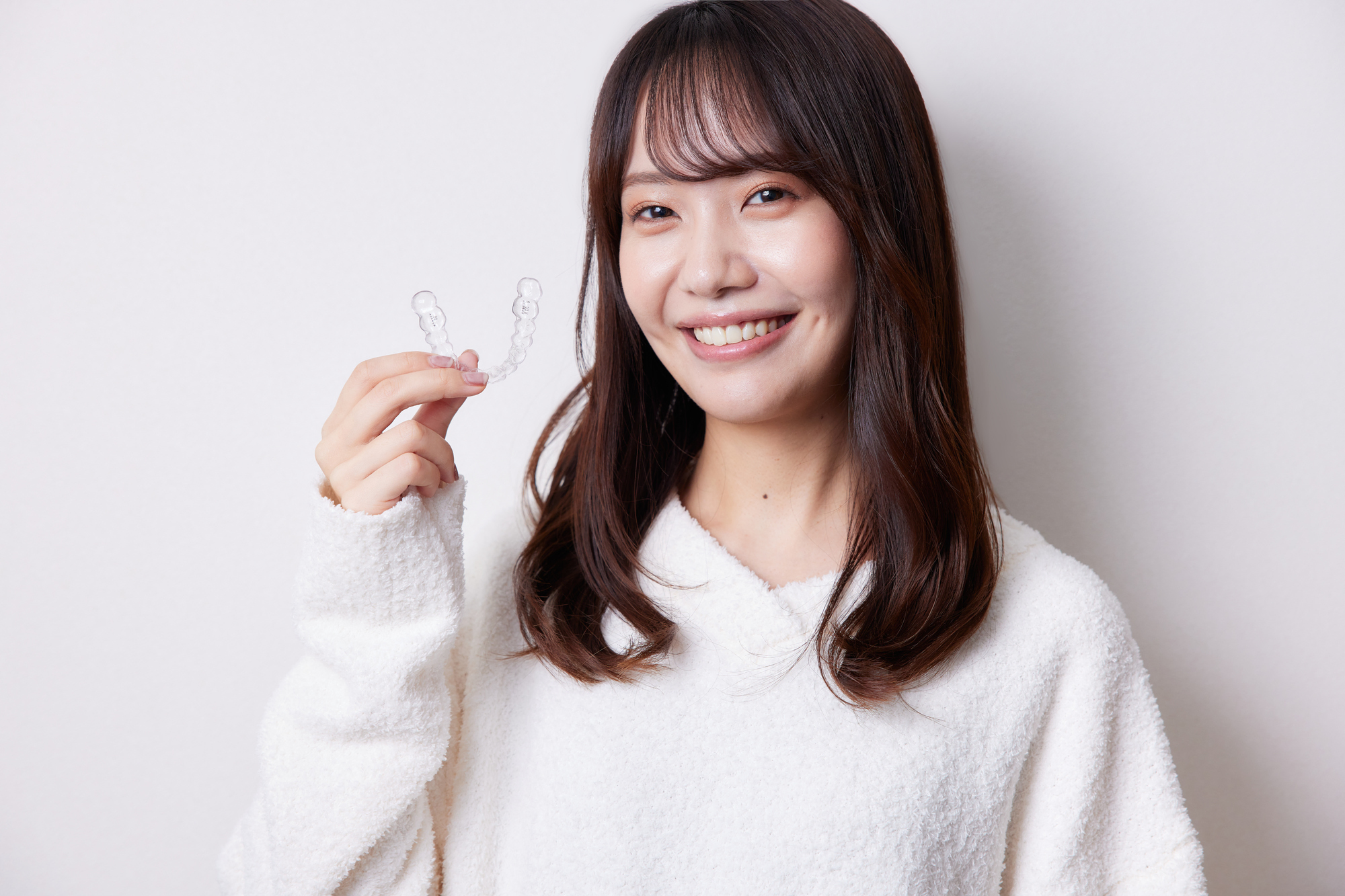 マウスピース型矯正装置を持つ女性
